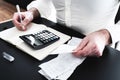 Man at desk with calculator, bills or sales slips and notpad