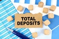 On documents with graphs and reports, there are cubes and cardboard with the inscription - Total deposits