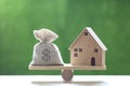 Finance Money bag and Model house on wood scale seesaw on natural green background Business investment and real estate