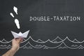 Finance, tax, business concept. hand holding sailing paper ship with text: double taxation