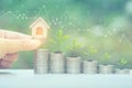 Finance,Woman hand holding model house with plant growing on stack of coins money and graph on natural green background, Interest Royalty Free Stock Photo