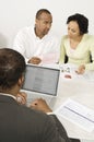 Financial Advisor Using Laptop With Couple In Discussion Over Documents Royalty Free Stock Photo