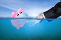 Financial Aid and rescue from debt problems for investments above water as a drowning pink piggy bank sinking in blue water