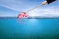 Financial Aid and rescue from debt problems for investments above water as a drowning pink piggy bank sinking in blue water