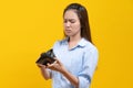 Financial bankruptcy girl opening empty wallet and worrying face isolated on yellow background