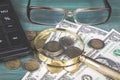 Financial concept. Calculator, magnifying glass, euro coins, british penny, dollar bills and glasses on green wood table