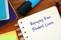 Financial concept meaning Repaying Your Student Loans with phrase on the piece of paper