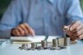 A businessman holds a pile of coins and presses a calculator to calculate business savings and investments. Business Risk and Coin