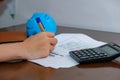Financial data analyzing hand writing and counting on calculator at home on wooden desk