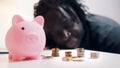 Financial decision, investments and savings. African american man looking into the coins in front of the piggy bank. Royalty Free Stock Photo