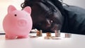 Financial decision, investments and savings. African american man looking into the coins in front of the piggy bank. Royalty Free Stock Photo