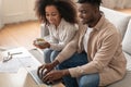 Black couple engaged with paperwork and laptop in living room Royalty Free Stock Photo
