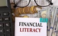 FINANCIAL LITERACY- words on a white piece of paper on the background of a calculator, pennies and glasses Royalty Free Stock Photo