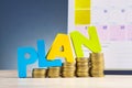 Word PLAN and stacking coins on wooden desk over beautiful reverberation gradient background