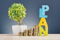 Word PLAN and stacking coins on wooden desk over beautiful reverberation gradient background