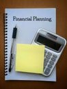 Financial planning text on notepad with pen, calculator and sticky note background.