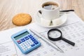 Financial printout, calculator, pen, magnifying glass, coffee an