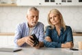 Financial Problems. Upset Senior Couple Showing Empty Wallet While Sitting In Kitchen Royalty Free Stock Photo