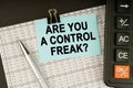 On financial reports lies a calculator, a pen and a sticker with the inscription - Are You a Control Freak