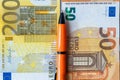 Financial settlements in the euro zone, concept, 50 and 200 euro banknotes stacked next to each other, between them an orange pen Royalty Free Stock Photo