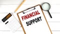 FINANCIAL SUPPORT words on clipboard, with calculator, magnifier and pencil on the white wooden background Royalty Free Stock Photo