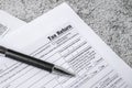 Financial time tax return forms with pen on stone table