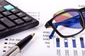 Financial tools, calculator, pen and spectacles over a report Royalty Free Stock Photo