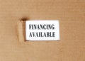 Financing. Available text on a white background appearing on a torn cardboard