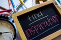 Find inspiration on phrase colorful handwritten on chalkboard, alarm clock with motivation and education concepts.