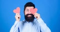 Find love with heart not eyes. Bearded man hiding eye with red heart. Hipster holding small hearts. valentine man