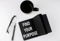 FIND YOUR PURPOSE written text in small black notebook with coffee , pen and glasess on white background. Black-white style