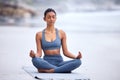 Finder inner peace. Full length shot of an attractive young woman meditating while practicing yoga on the beach. Royalty Free Stock Photo