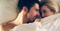 Finding comfort in each other. High angle shot of an affectionate young couple lying in bed together. Royalty Free Stock Photo