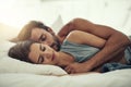 Finding comfort in his arms. an affectionate young couple sleeping in their bed.