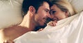 Finding comfort in one another. High angle shot of an affectionate young couple lying in bed together. Royalty Free Stock Photo