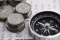 Finding my way into the market. Studio shot of coins and a compass on the business section of a newspaper.