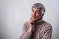 Finding perfect solution. Mature handsome man with gray hair and wrinkles holding his finger on cheek looking thoughtful and havin Royalty Free Stock Photo