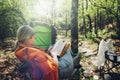 Finding solitude in wilderness concept. Young woman resting in forest, sitting in camp chair and reading book Royalty Free Stock Photo