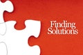 FINDING SOLUTIONS text with jigsaw puzzle on red background Royalty Free Stock Photo