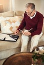 Finding ways to make his existing savings last. a senior man working out a budget while sitting on the living room sofa. Royalty Free Stock Photo