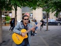 Fine acoustic guitarist playing to members of the public on busy Montreal streets in autumn.