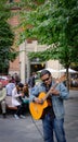 Fine acoustic guitarist playing to members of the public on busy Montreal streets in autumn.