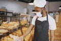 Fine African American man in mask offering pastry