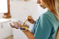 Fine art school. Closeup of artist hands holding wooden palette, mixing acrylic paint with brush.Artist woman with Royalty Free Stock Photo