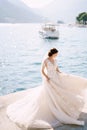 The bride in a wedding dress is dancing on the pier, waving a dress. Fine-art wedding photo in Montenegro, Perast. Royalty Free Stock Photo