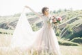 Fine art wedding photography. Beautiful bride with bouquet and dress with train in nature Royalty Free Stock Photo
