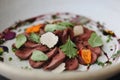 Fine Dining Meal on Plate in Restaurant. Beef Carpaccio with Black Truffles and Herbs. Closeup