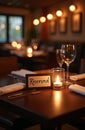 Fine dining table setting displays reserved sign, glasses, candle. Setup in warm lighting. Tableware arranged for event, dinner Royalty Free Stock Photo