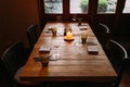 Fine dining wooden table with cutleries, wine glasses, napkins and naperies with lighted candle on the table.