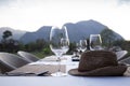 A fine dinner table set with high wine glass and utensils with a weave hat on the table with mountain view.